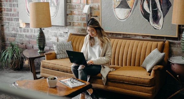 girl sitting on couch typing on laptop